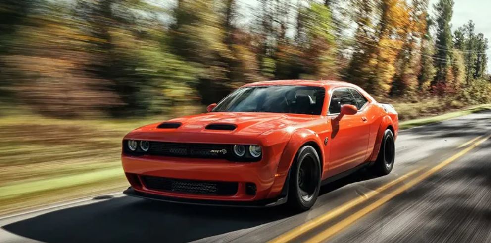 An orange 2022 Dodge Challenger being driven on the highway. | Paint Repair in Central Arkansas | Crain Automotive Team Collision