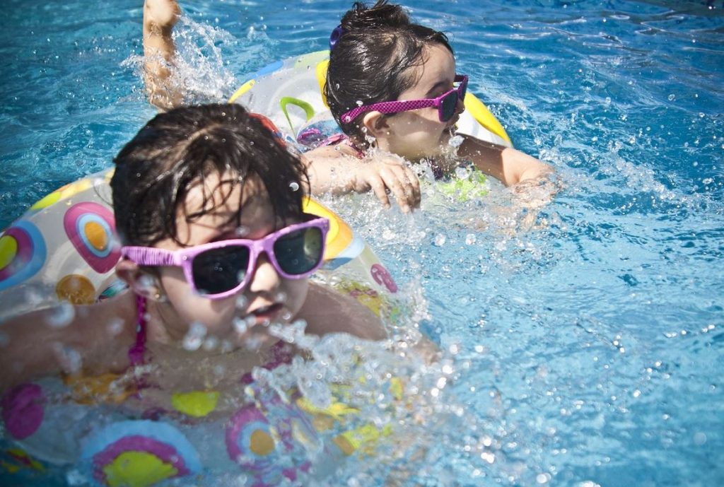 Two little girls with floaties in a swimming pool. | Summer activities around Little Rock, AR | Crain Automotive Team Collision